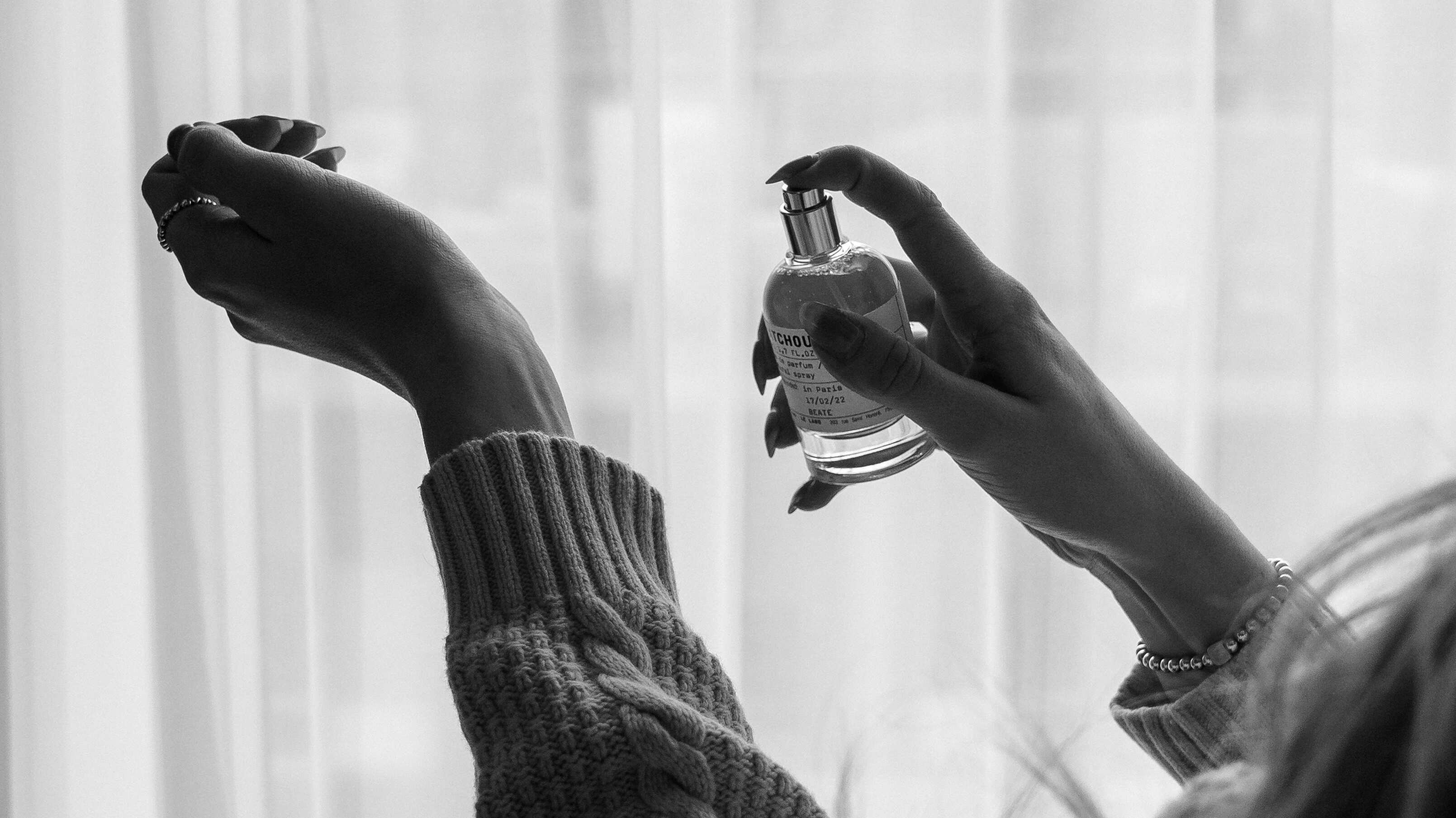 Imagem em preto e branco de mulher borrifando perfume no pulso