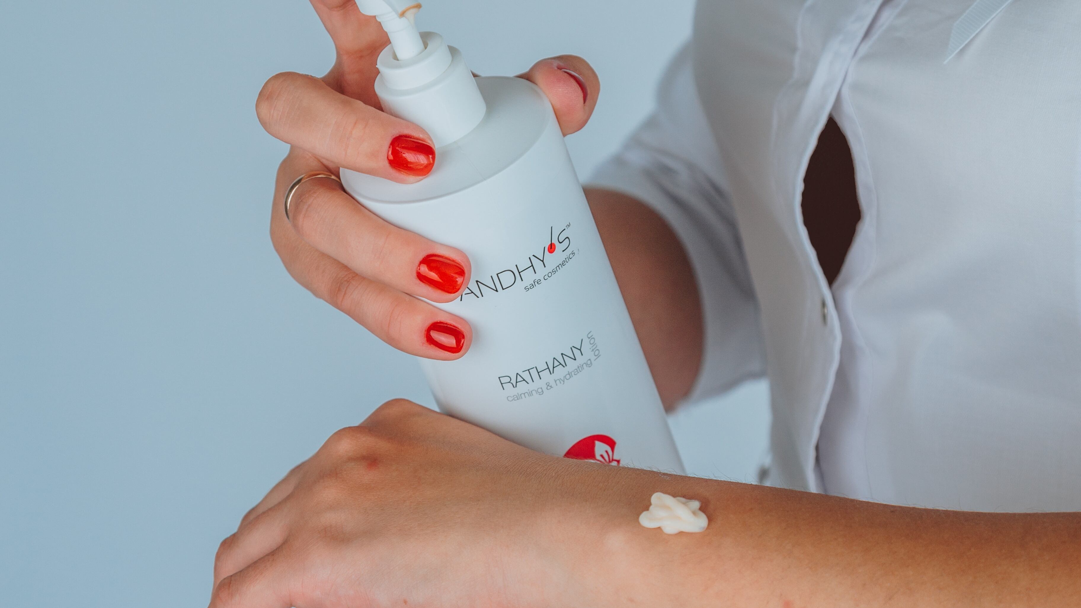 Mulher segurando fraco de hidratante e passando no braço