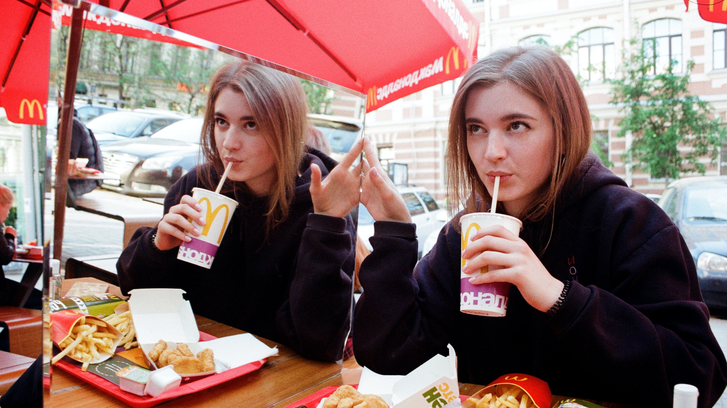 Mulher tomando refrigerante no McDonald's segurando espelho