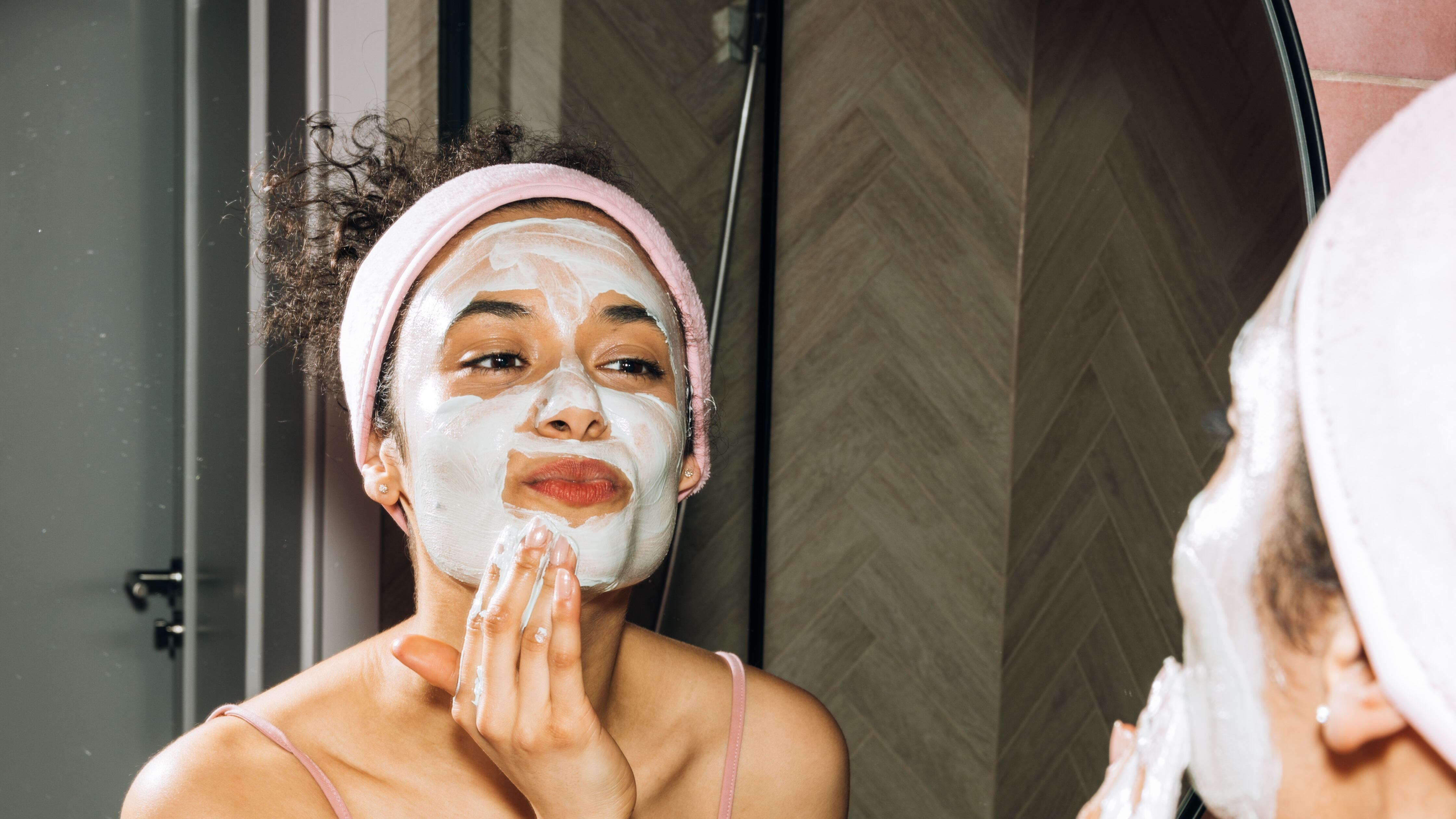 Mulher em frente ao espelho realizando procedimento de skincare