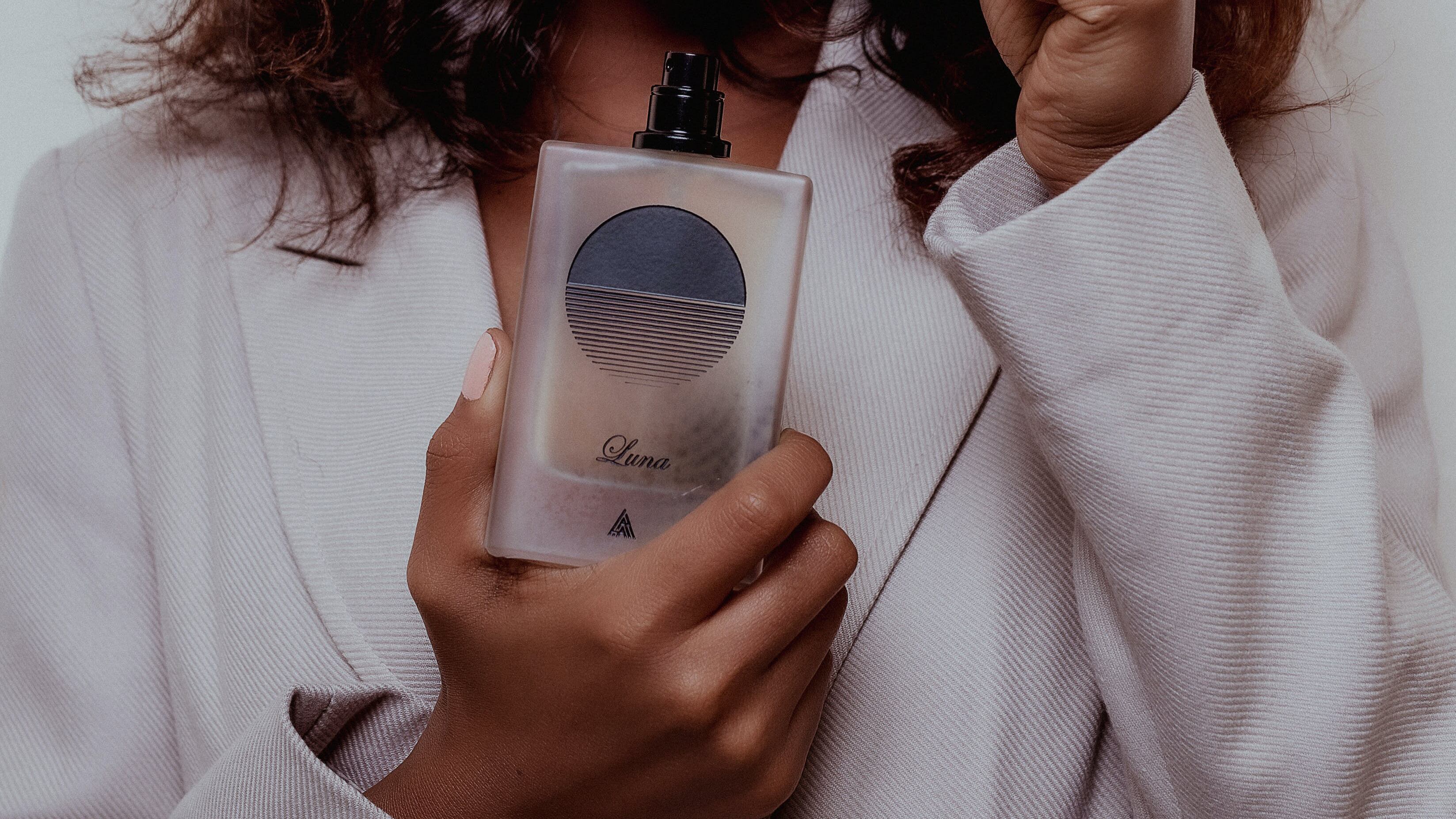 Mulher negra segurando frasco de perfume