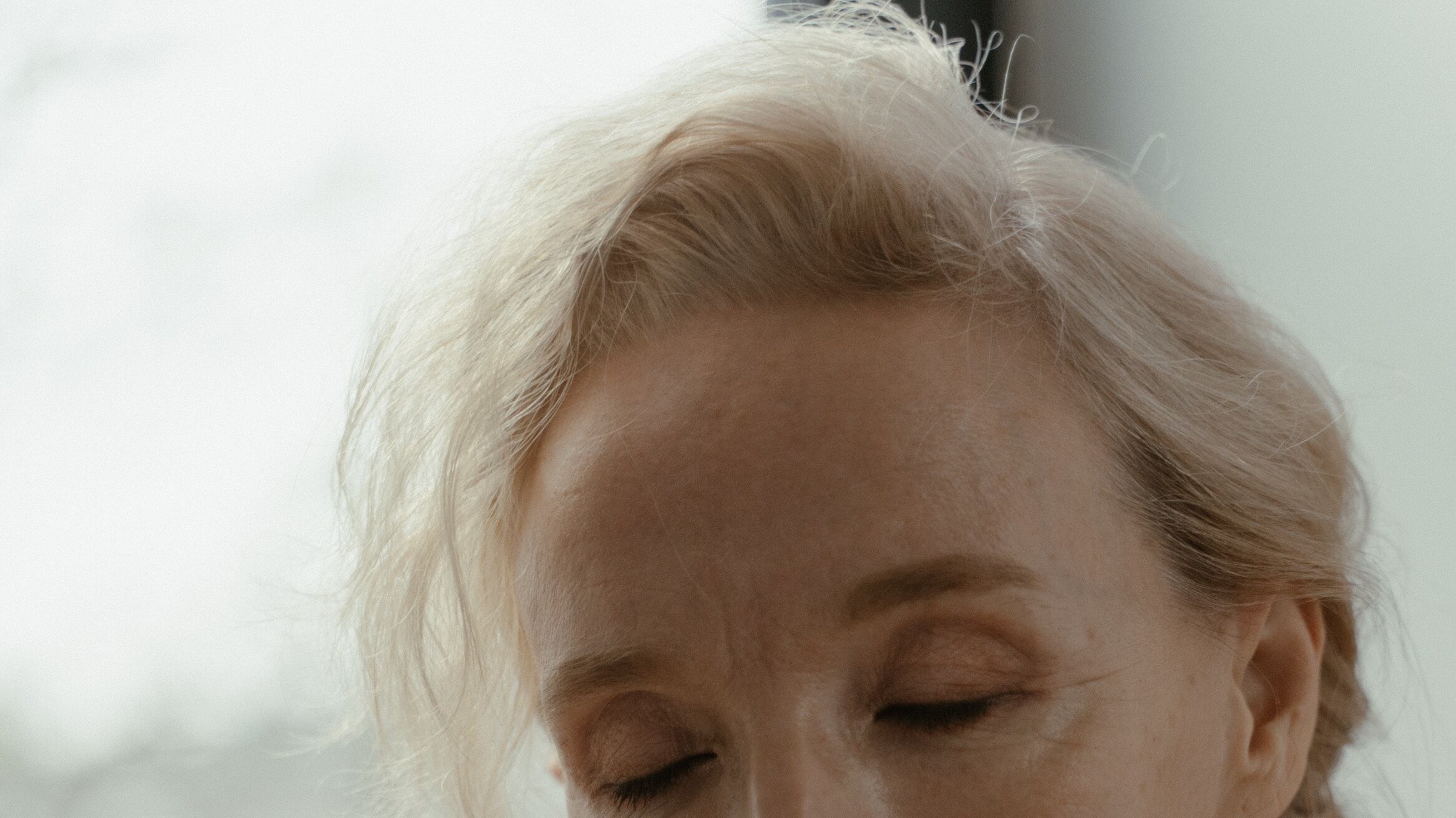 Mulher mais velha de cabelos brancos sentindo aroma de perfume