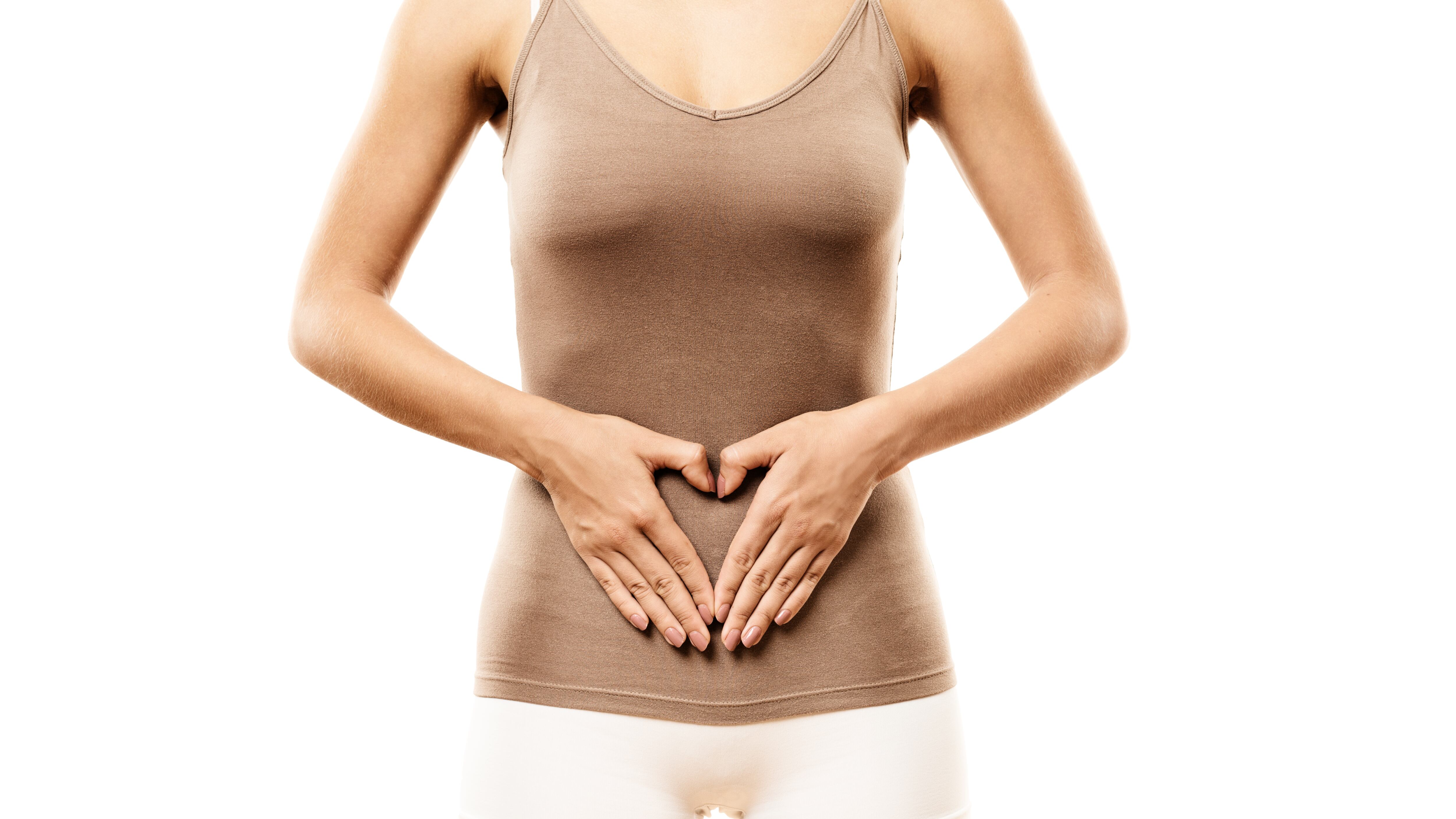 Mulher com blusa marrom e short branco com a mão na barriga