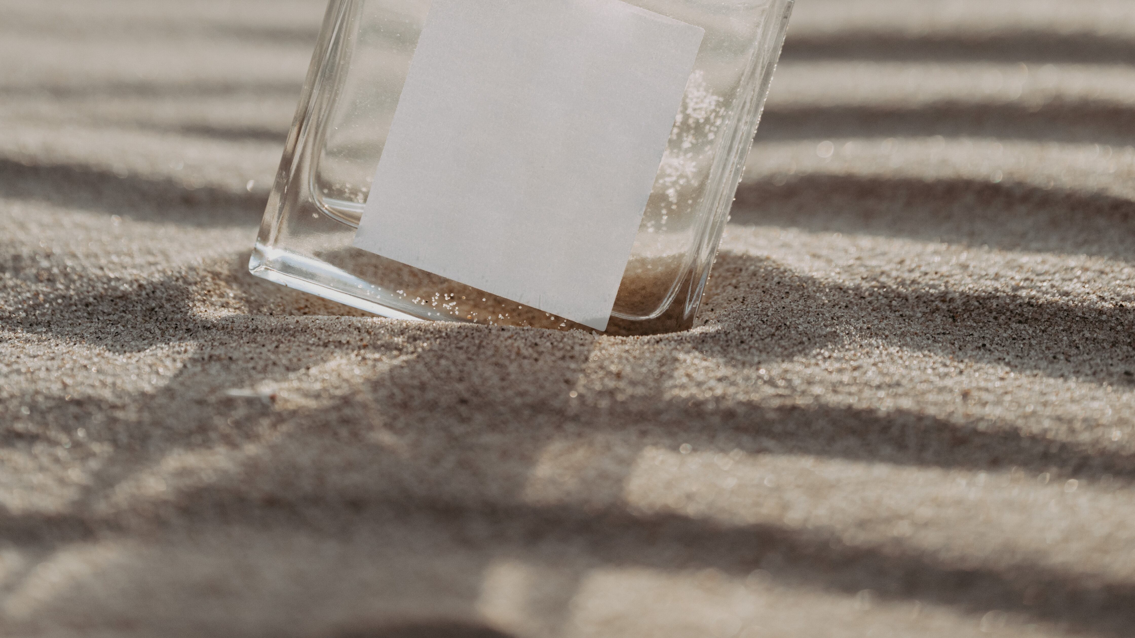 Frasco de perfume transparente na areia da praia