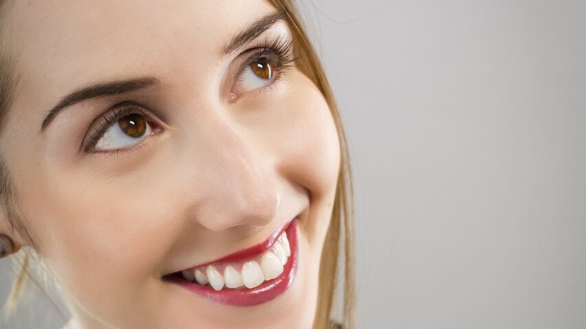 Mulher segurando frasco de perfume preto