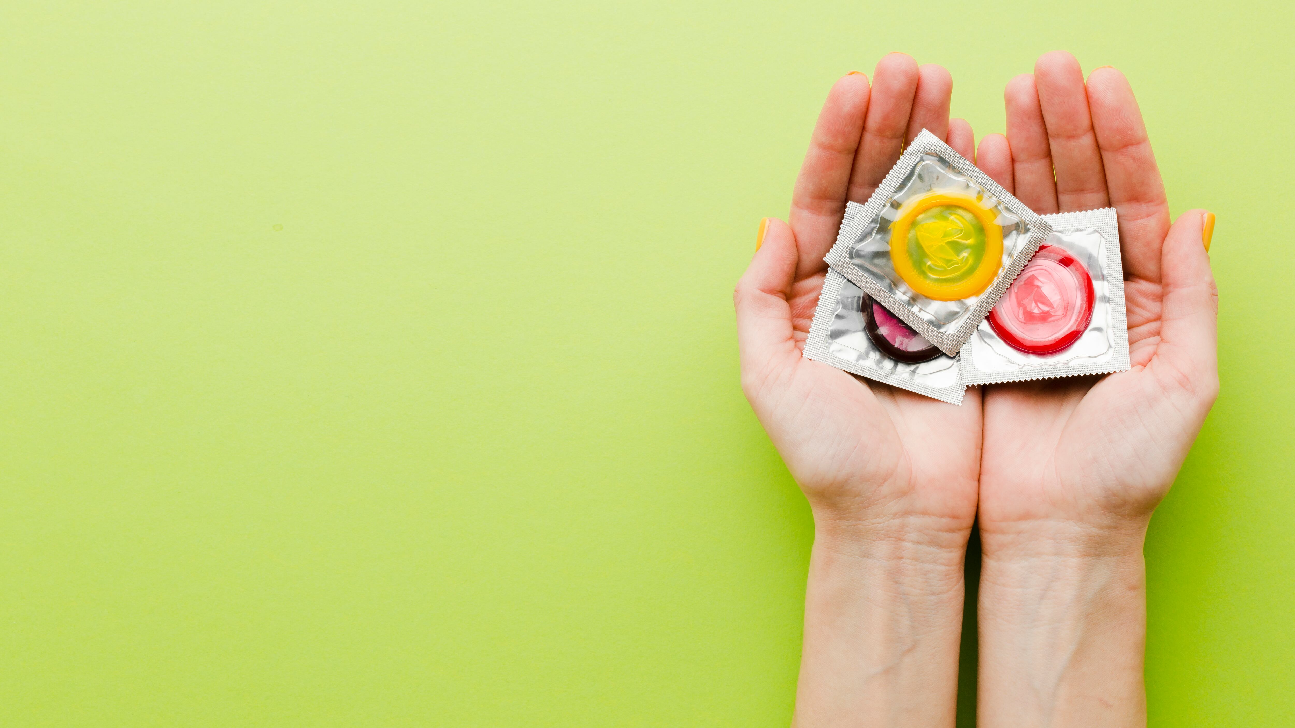 Mão segurando camisinhas