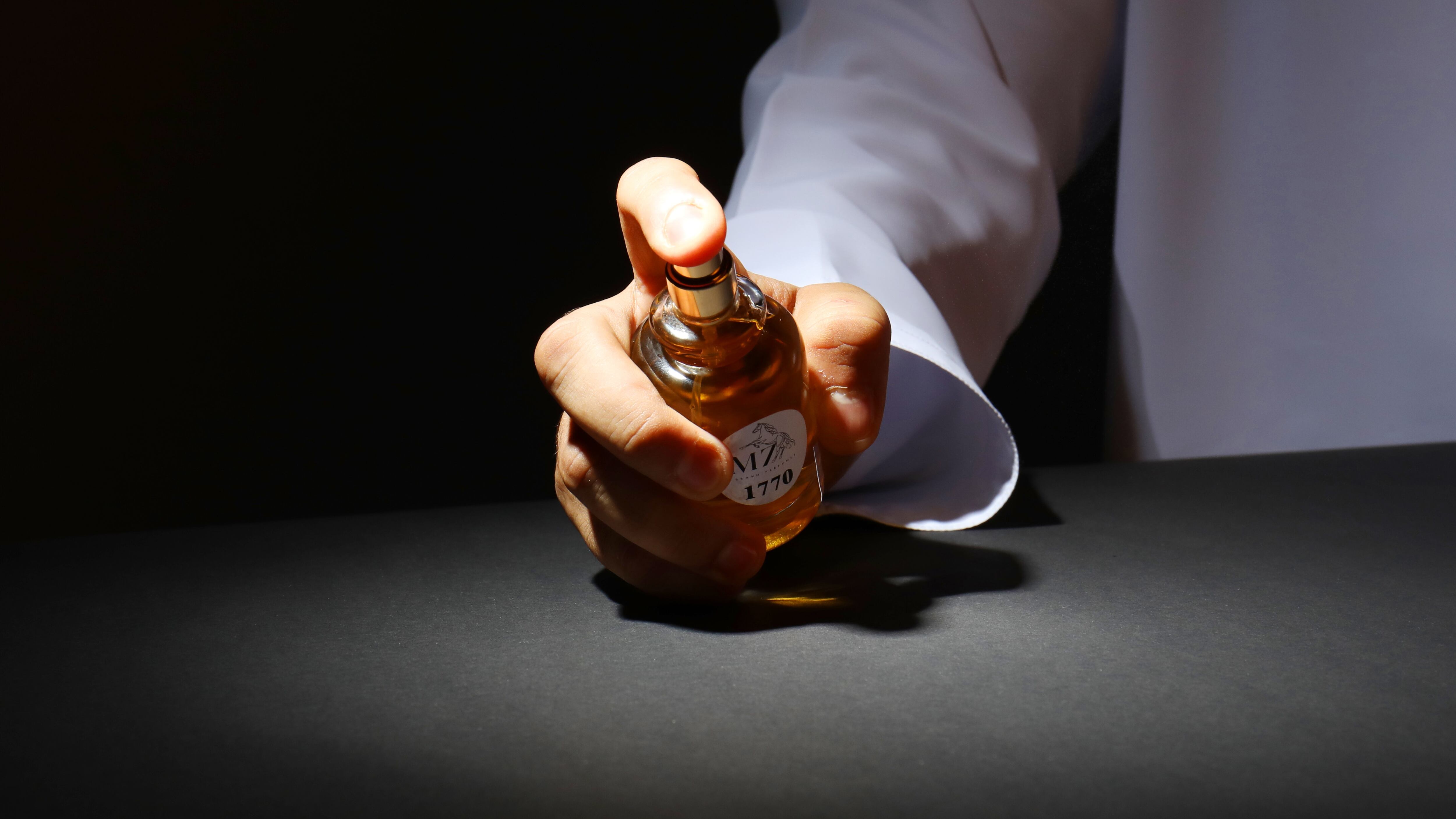 Silhueta de braço masculino apertando borrifador de perfume