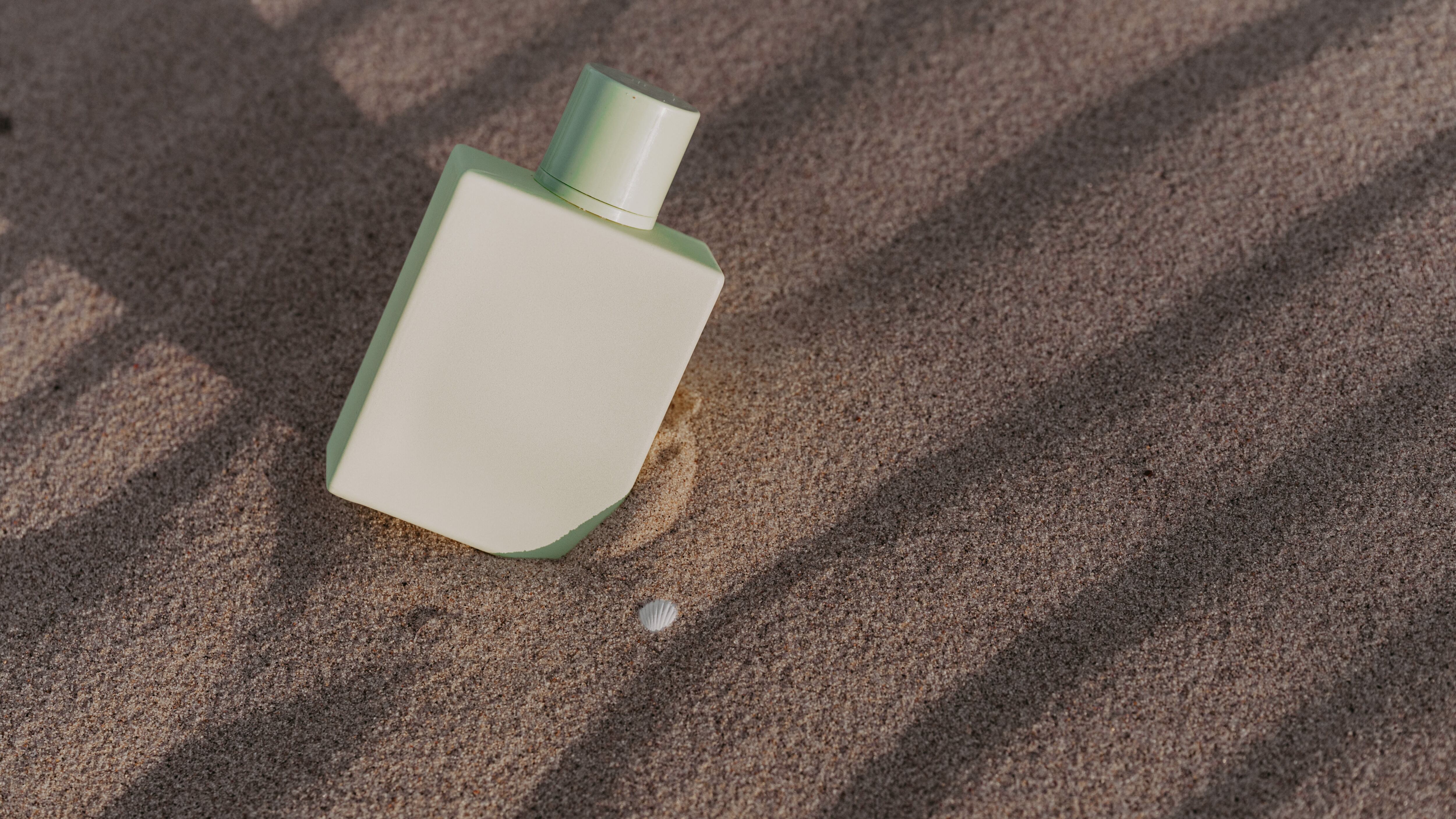 Frasco de perfume verde na areia da praia