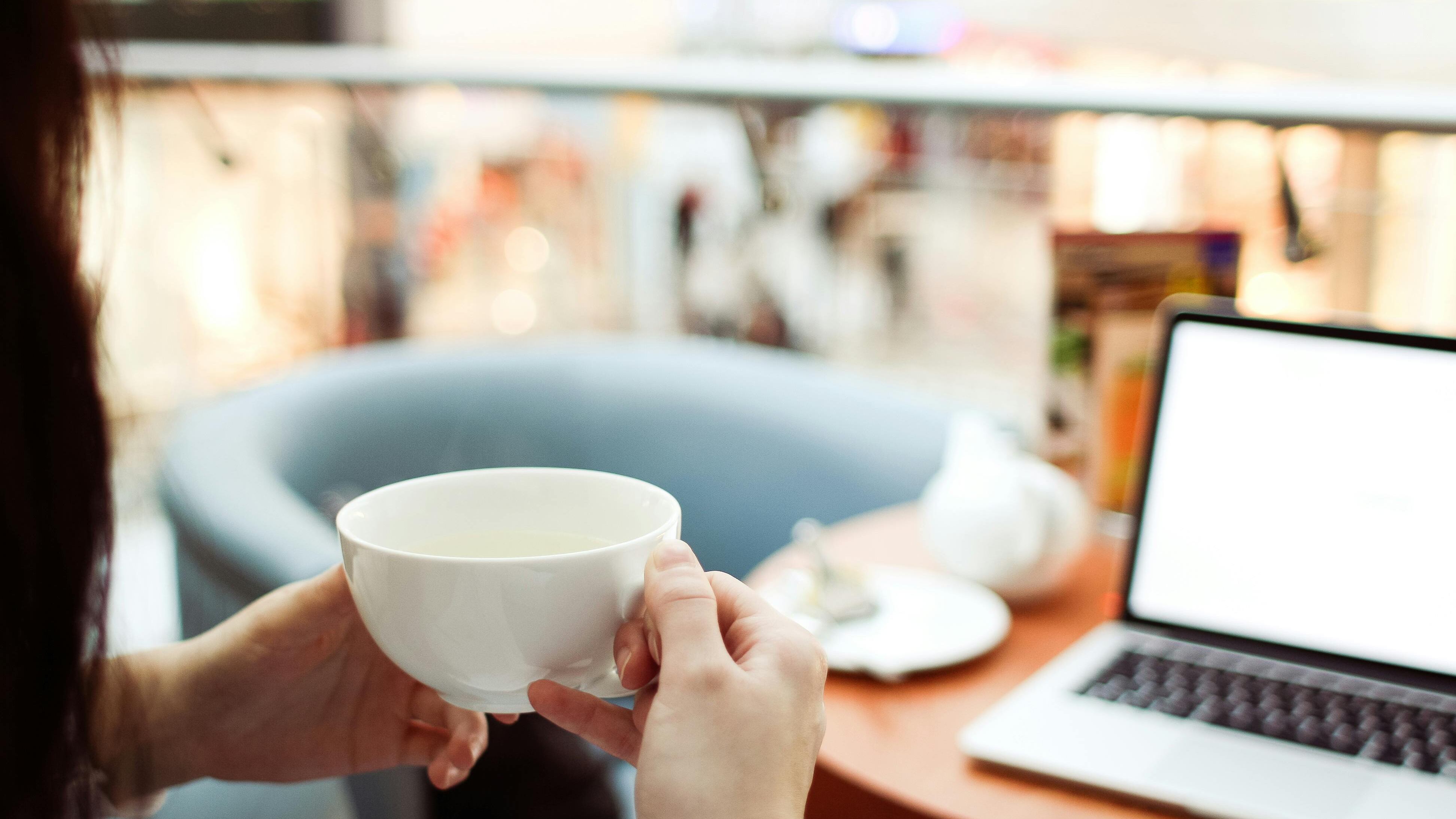 Mulher bebendo café em frente ao computador