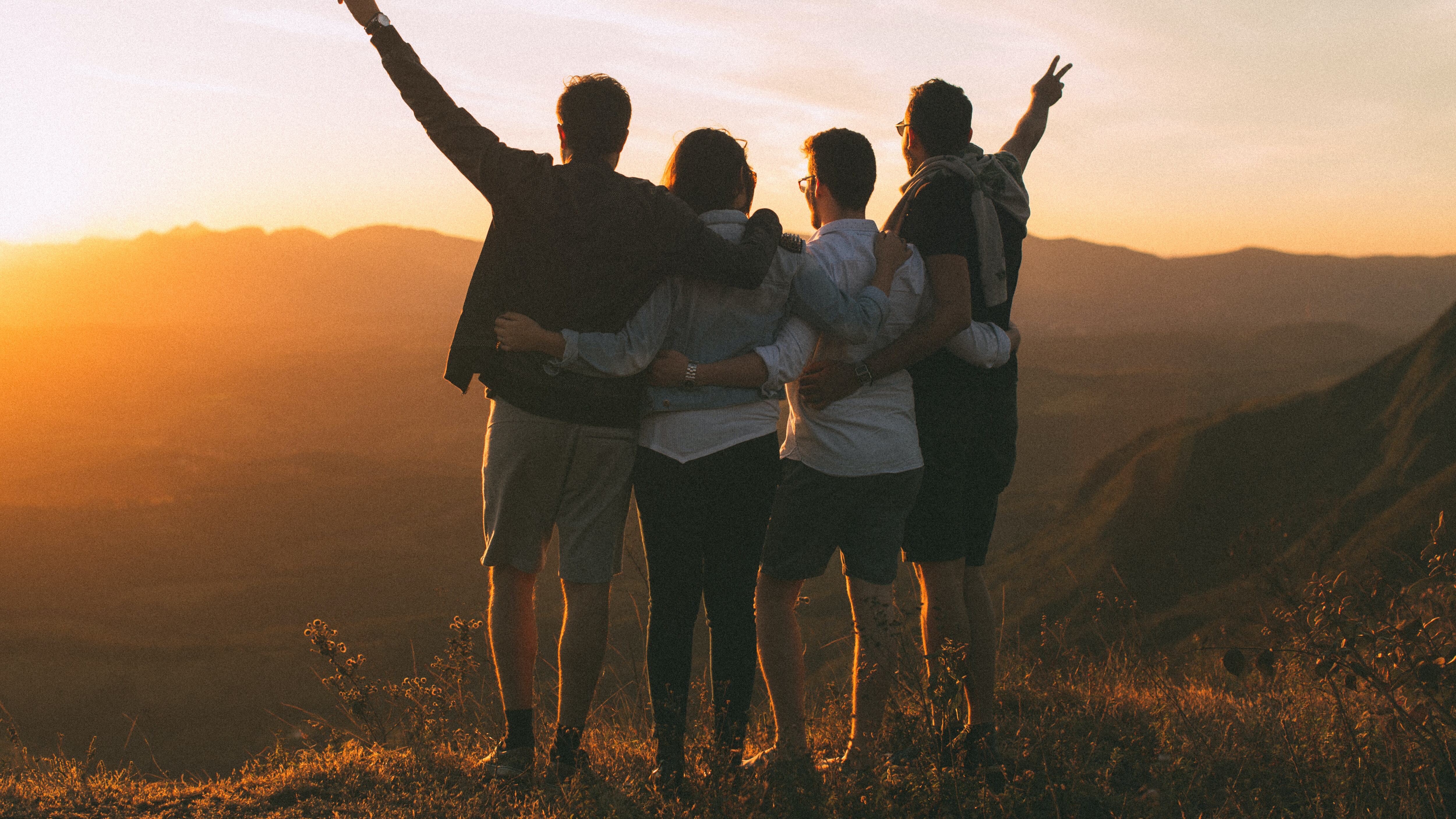Amigos abraços admirando o horizonte e o por do sol