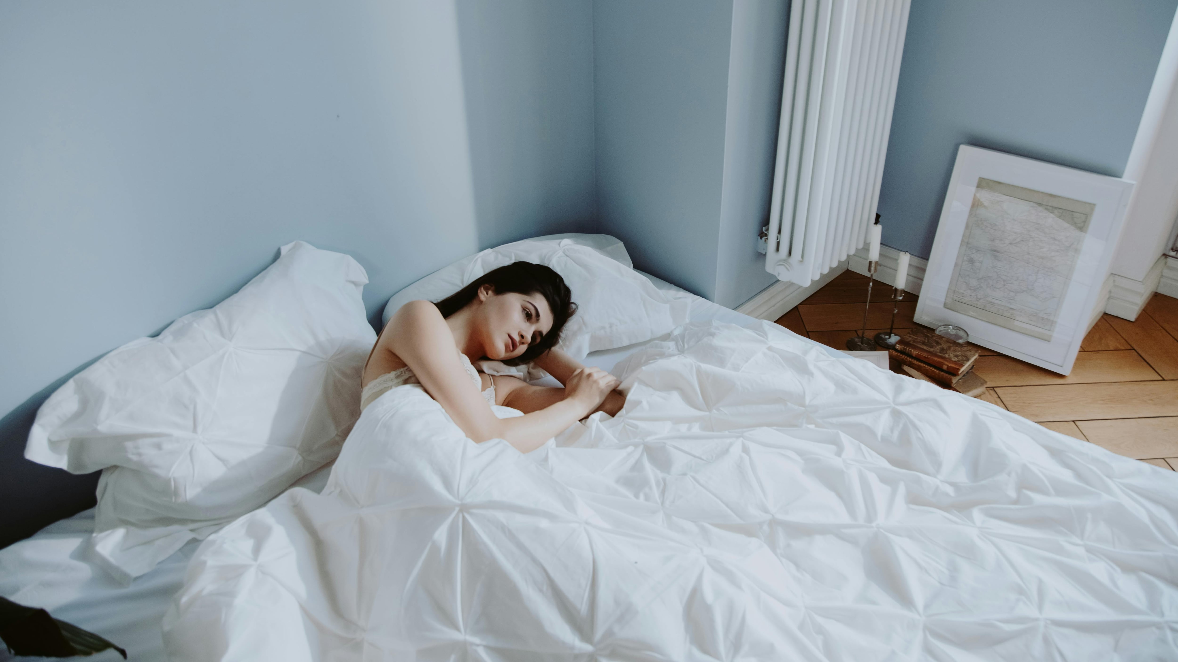 Mulher na cama deitada de olho aberto