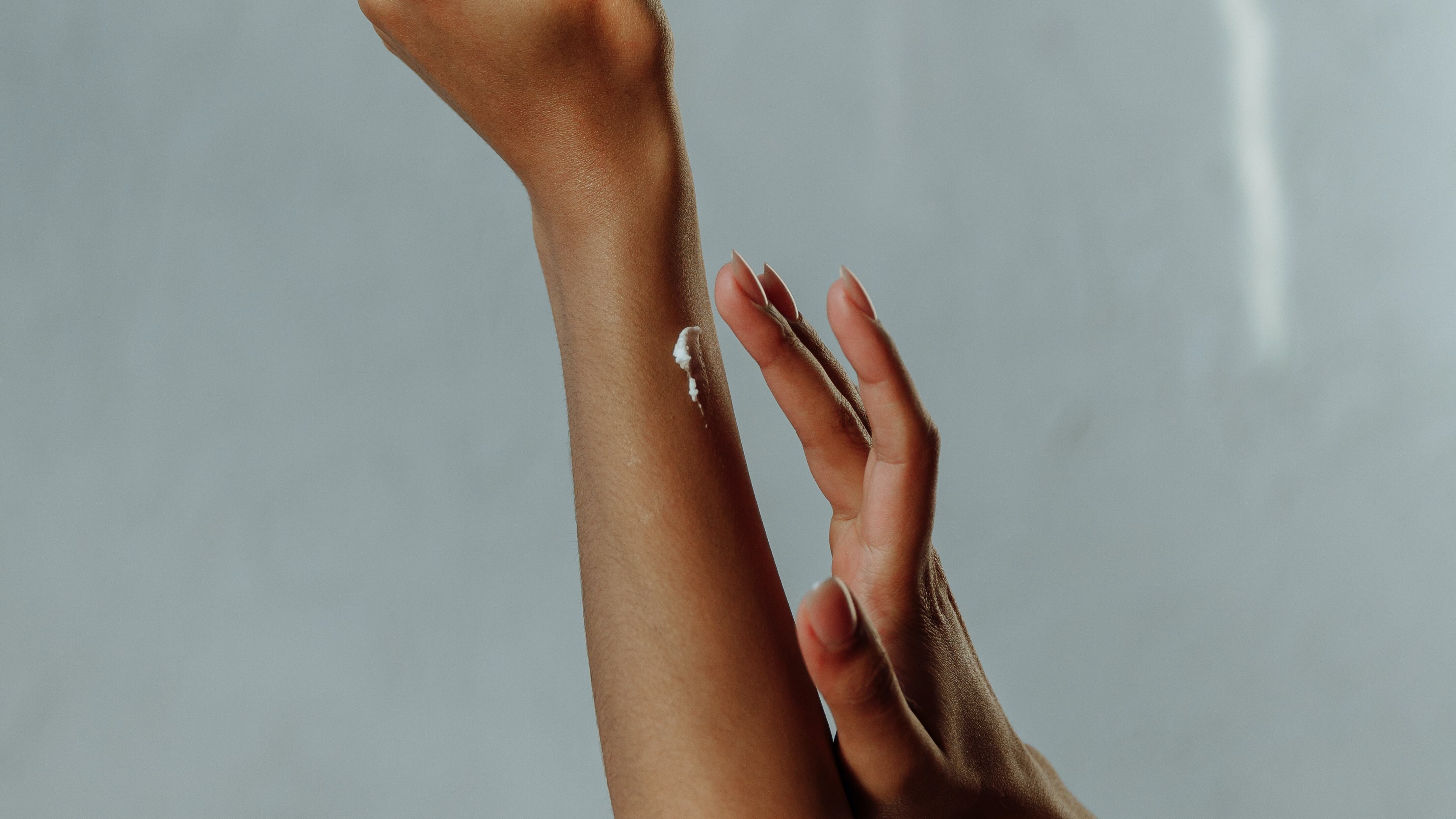 Silhueta feminina passando hidratante no braço